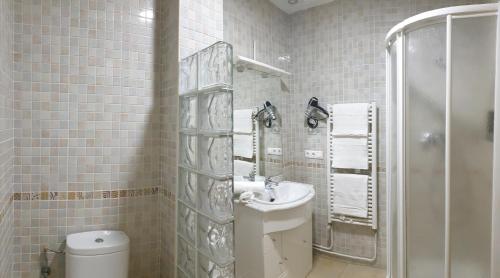 a white tiled bathroom with a sink and a shower at Portales de Pizarro in Béjar