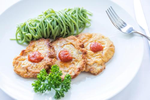 a white plate with two pieces of meat and green beans at Hotel & Spa Cacciatori in Cademario