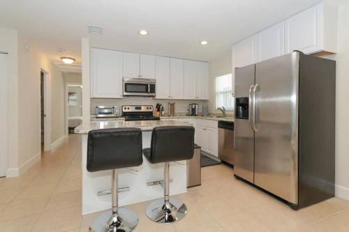 a kitchen with a stainless steel refrigerator and two bar stools at Lovely Cottage - Close to Siesta, Shops & Dining in Sarasota
