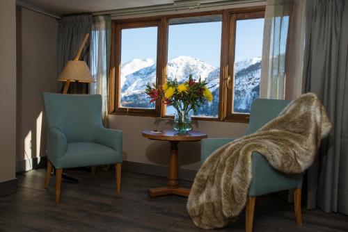 a room with two chairs and a table with a vase of flowers at Hotel Termas Chillán in Nevados de Chillan