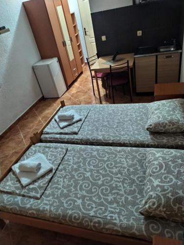 two beds in a room with a kitchen and a table at Apartments DEA in Bar