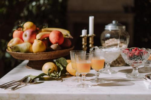 a table with glasses of juice and a basket of fruit at Villino di Porporano in Parma