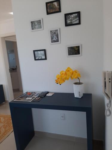 Un escritorio azul con un jarrón de flores amarillas. en Apartamento Santa Ana en São Joaquim