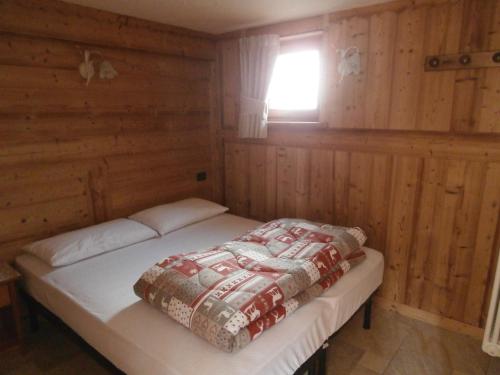 a bed in a wooden room with a window at Petites Fleurs Cogne in Cogne