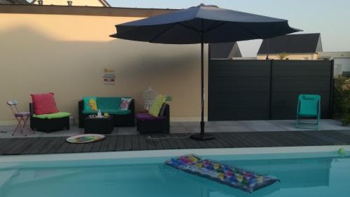 a patio with chairs and an umbrella and a pool at La casita de Vanessa in Changé