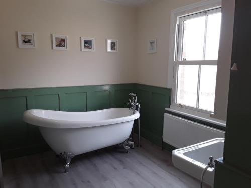 a green and white bathroom with a tub and a window at The Haven in Gateshead