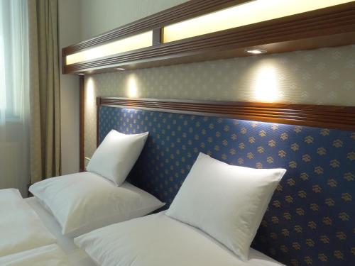 1 dormitorio con 2 camas y almohadas blancas en Centrum Hotel en Debrecen