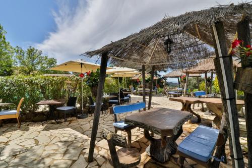 a restaurant with tables and chairs and a straw umbrella at L'Estirado des Adrets in Les Adrets de l'Esterel