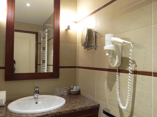 a bathroom with a sink and a phone on the wall at Centrum Hotel in Debrecen