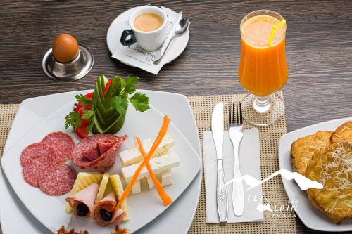 a table with two plates of food and a glass of juice at Vila Alpin in Straja