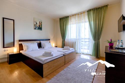 ein Schlafzimmer mit einem Bett und einem großen Fenster in der Unterkunft Vila Alpin in Straja