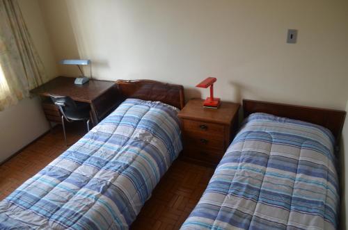 a bedroom with two beds and a desk with a lamp at Pousada das Orquideas de Jau in Jaú
