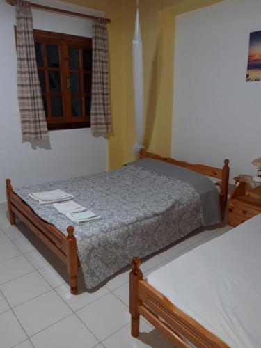 a bedroom with two beds and a window at Koutadelias rooms in Kálamos