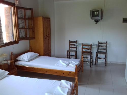 a room with two beds and a table and chairs at Koutadelias rooms in Kálamos