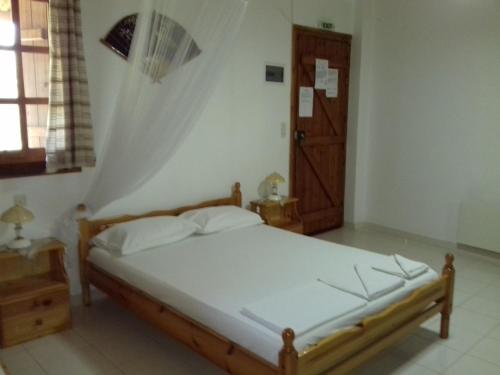 a bedroom with a bed and a wooden door at Koutadelias rooms in Kálamos