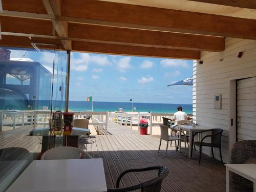 a person sitting at a table on a deck with the beach at Playa de Consolaçao in Consolacao