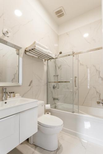 a white bathroom with a toilet and a shower at Parc Avenue Lofts in Montréal