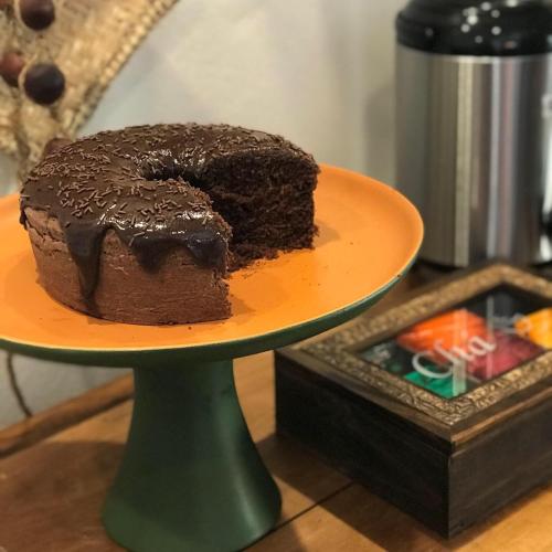 Un pastel de chocolate en un plato naranja sobre un soporte. en Pousada Aroeira, en Barra do Sahy