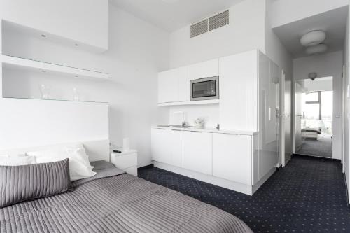 een witte slaapkamer met een bed en een wastafel bij Platinum Sky in Wrocław