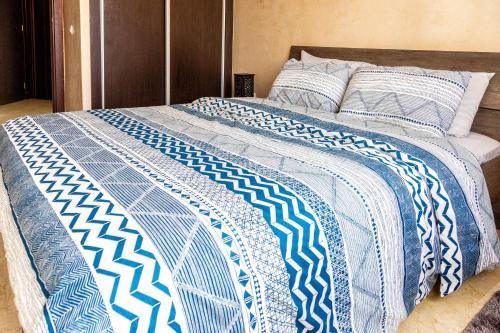a bed with a blue and white comforter on it at Appartement Panoramique in Casablanca