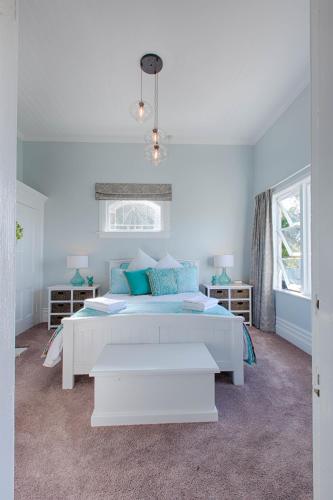 a white bedroom with a large bed with blue pillows at Aqua On Reed in Oamaru