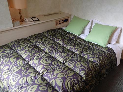 a bed in a hotel room with green pillows at Hotel A.P in Toyonaka