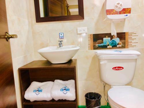 a bathroom with a sink and a toilet with towels at Hotel La Cumbre in Baños