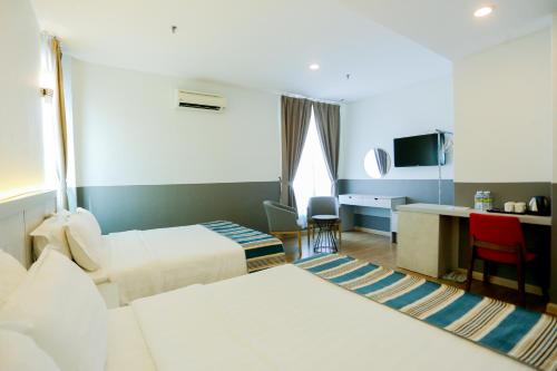 a hotel room with two beds and a desk at The Explorer Hotel in Melaka