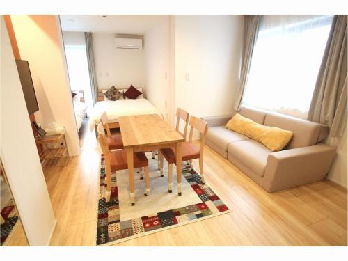 a living room with a dining room table and a couch at Apartment Hotel Tenjin TUMUGU in Fukuoka
