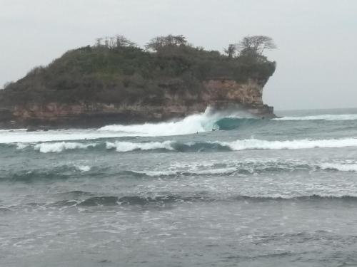 an island in the ocean with waves in the water at Harry's Ocean House Watukarung Homestay in Kalak