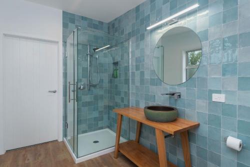 een badkamer met een wastafel en een glazen douche bij The Yellow House in Kaka Point