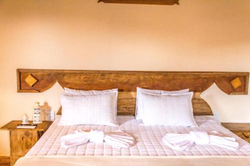 a bedroom with a bed with white sheets and pillows at Pé da Serra Suítes in Lavras Novas
