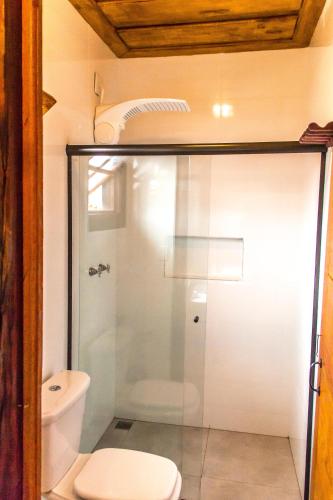 a bathroom with a glass shower with a toilet at Pé da Serra Suítes in Lavras Novas