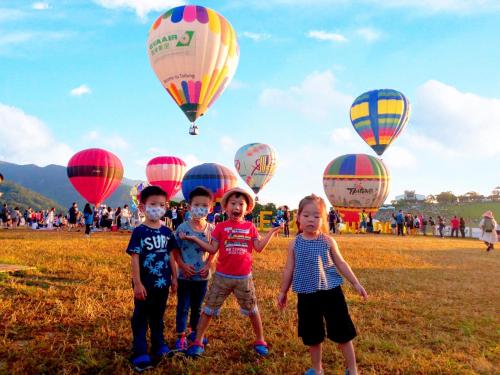 three children standing in a field with hot air balloons at 艾希兒民宿 I'm Here hostel l小家庭包棟首選l 台東包棟 l台東火車站l背包單人 in Taitung City