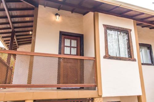 a house with a balcony with two windows at Pé da Serra Suítes in Lavras Novas