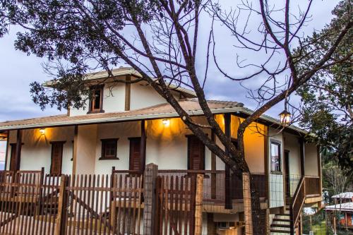 a house with a wooden fence in front of it at Pé da Serra Suítes in Lavras Novas