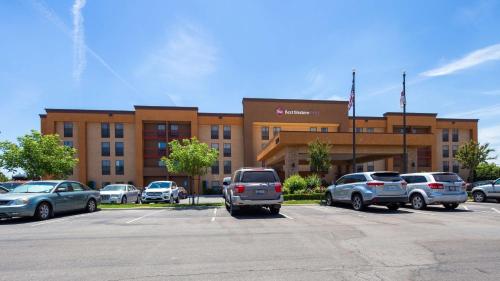 a building with cars parked in a parking lot at Best Western Plus Fresno Airport Hotel in Fresno