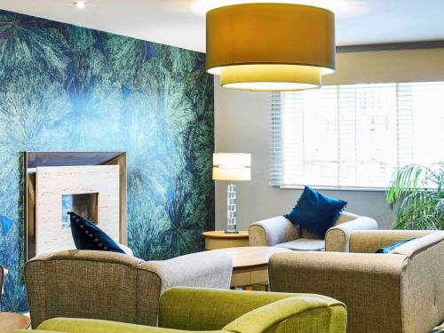 a living room with couches and a fire place at Mercure Newbury West Grange Hotel in Thatcham