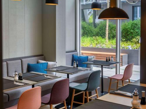 a restaurant with tables and chairs and a window at Mercure München City Schwabing in Munich