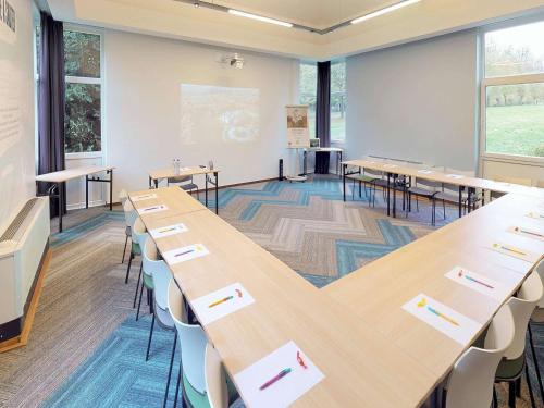 a classroom with rows of tables and chairs at ibis Styles Louvain-la-Neuve Hotel and Events in Louvain-la-Neuve
