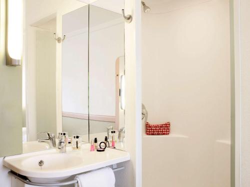 a bathroom with a sink, mirror, and toilet at Ibis Budget Portsmouth in Portsmouth