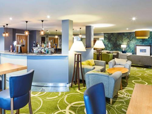 a hotel lobby with a bar and tables and chairs at Mercure Newbury West Grange Hotel in Thatcham