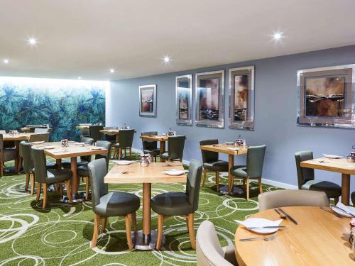 a dining room with wooden tables and chairs at Mercure Newbury West Grange Hotel in Thatcham