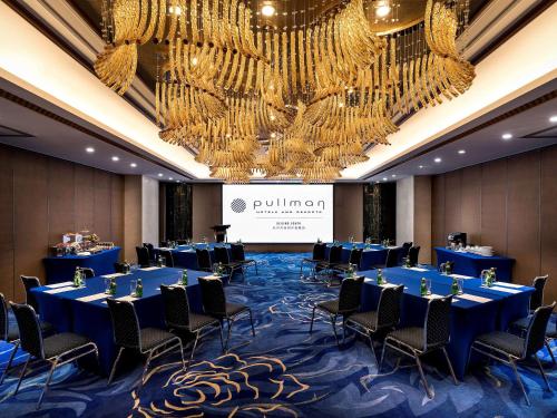 a conference room with blue tables and chairs and chandeliers at Pullman Beijing South in Daxing