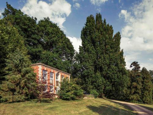 a building in the middle of a forest of trees at Mercure Gloucester Bowden Hall Hotel in Gloucester