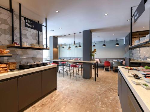 a large kitchen with tables and chairs in a restaurant at Mercure München City Schwabing in Munich