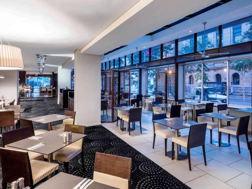 a restaurant with tables and chairs and windows at Pullman Brisbane King George Square in Brisbane