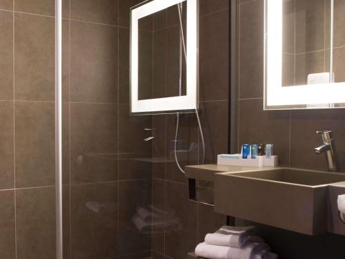 a bathroom with a shower and a sink and a mirror at Novotel Manchester Centre in Manchester