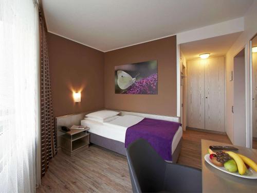 a bedroom with a bed, a desk, and a painting on the wall at Mercure Hotel Hameln in Hameln