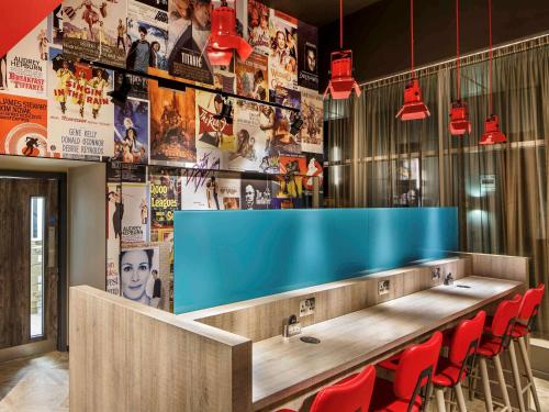 a bar with red chairs and a blue counter at ibis Styles London Ealing in London
